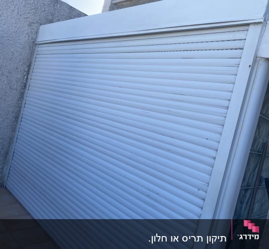 תריס גלילה לבן סגור על קיר חיצוני